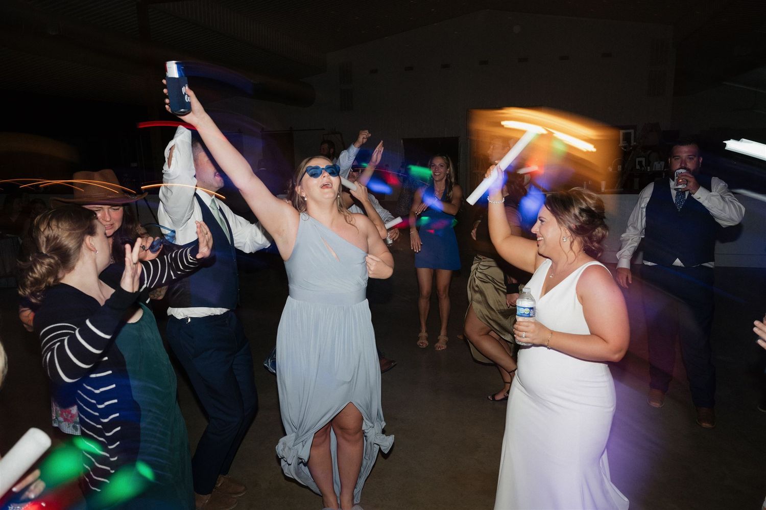 Wedding reception dance floor filled with guests holding light-up accessories and dancing.