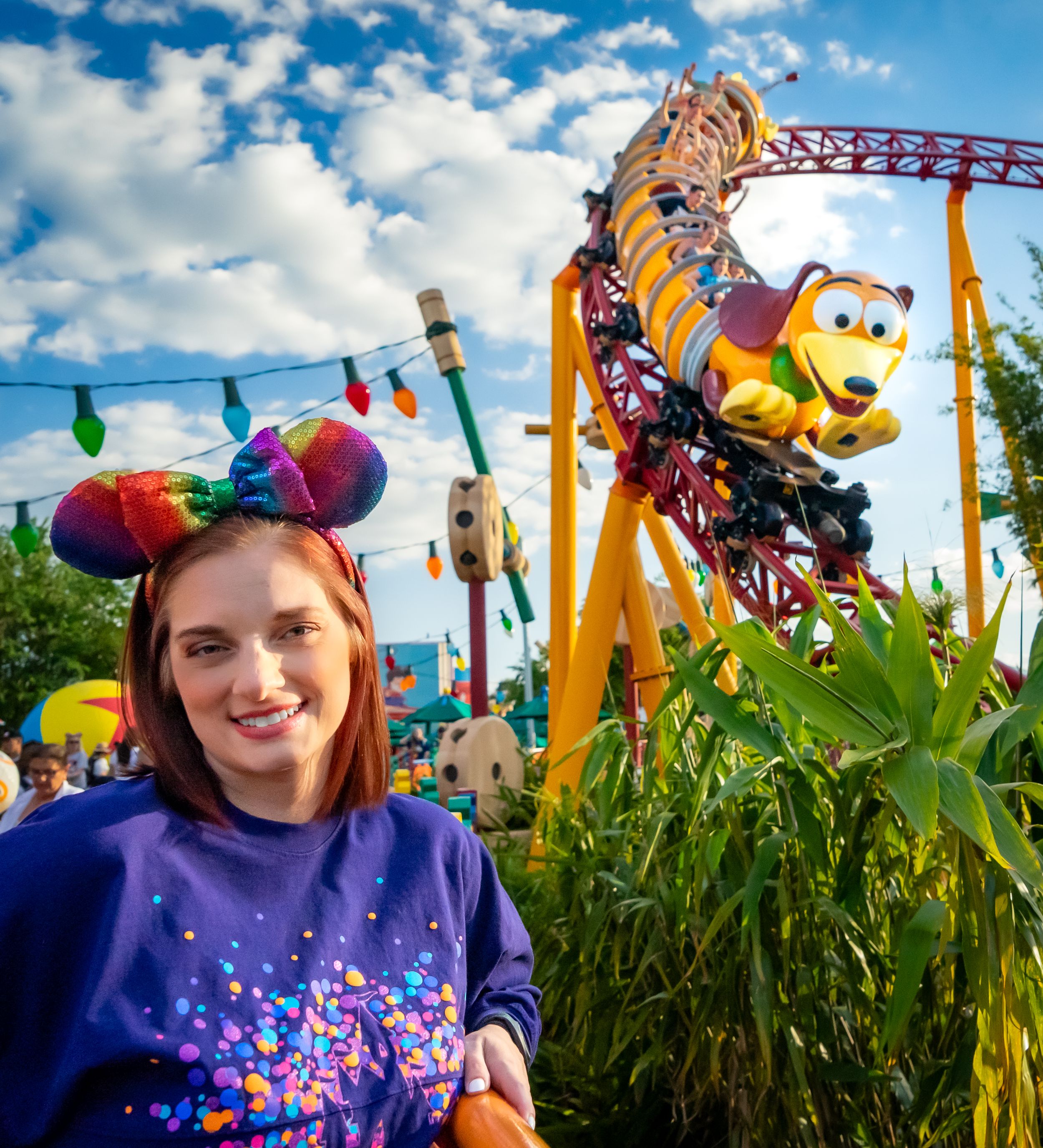 Colorful theme park scene with Toy Story Land decorations and blue sky background.