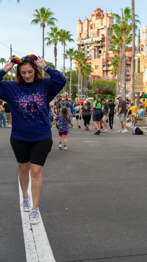 Theme park visitor walking along white line with Tower of Terror building in background.
