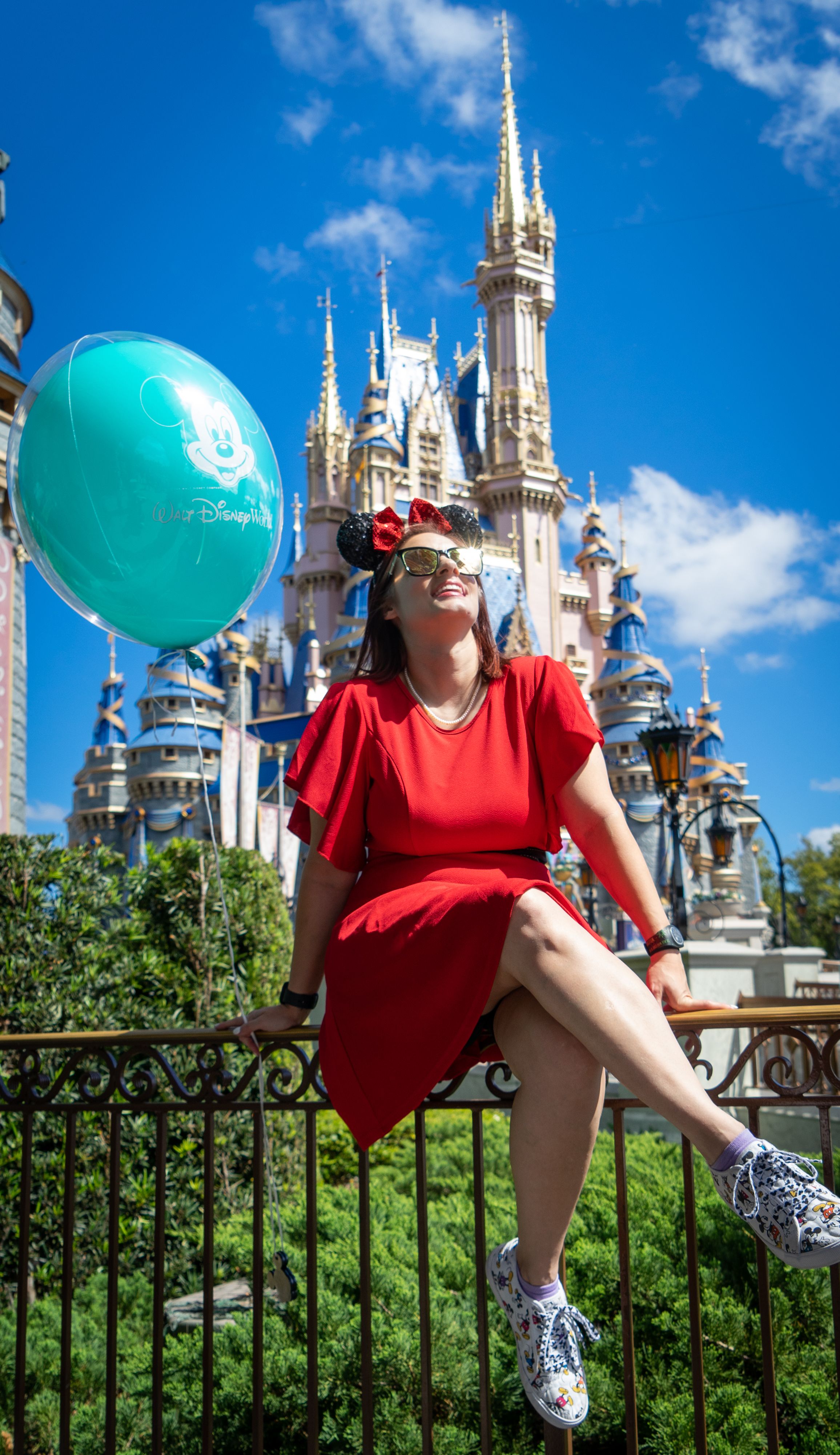 Playful pose with teal Disney balloon in front of Magic Kingdom castle.