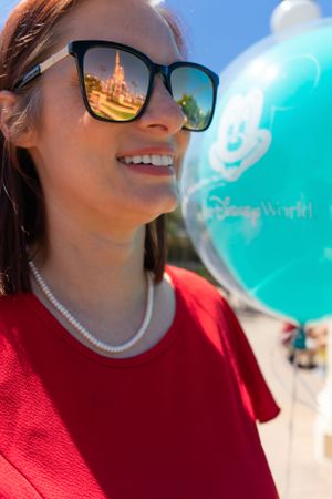 Close-up shot with teal Disney World balloon against bright blue sky.