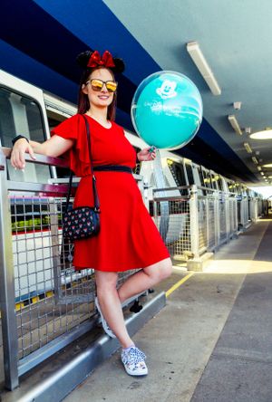 Red dress pose along monorail platform railing at Disney World.