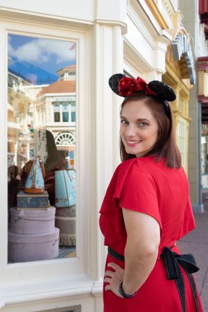 Red dress and Mickey Mouse ears outfit captured against white storefront architecture at Disney World.