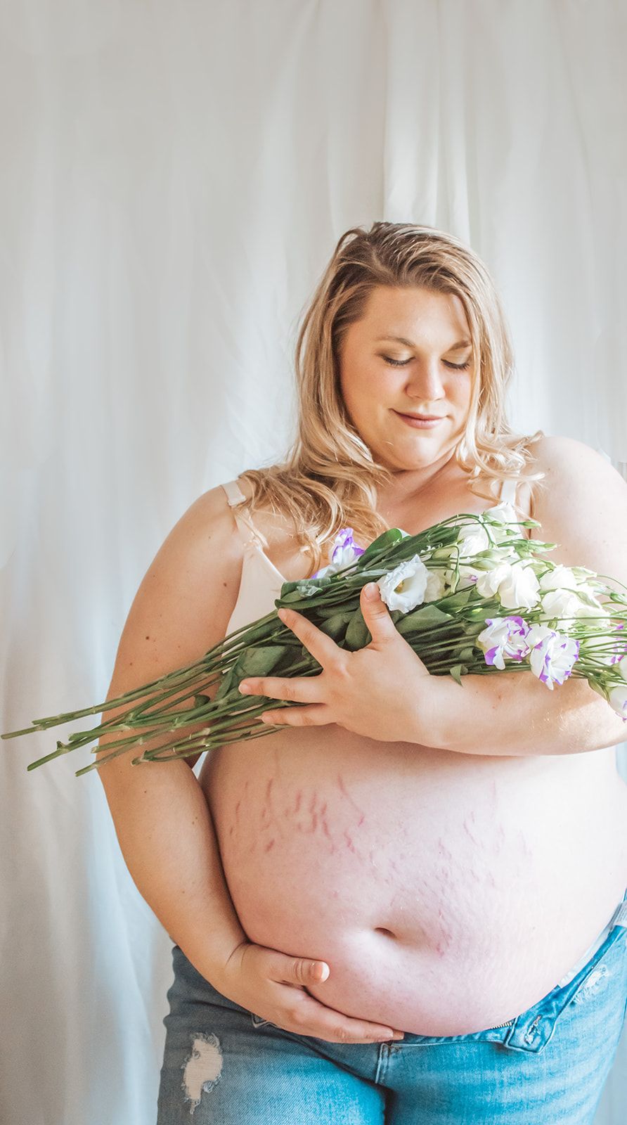 soon to be mom studio session holding flowers and cuping belly in maine