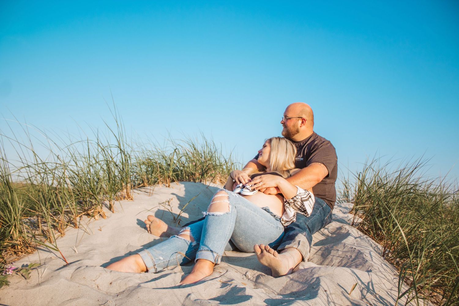 soon to be parents laying on a beach in maine