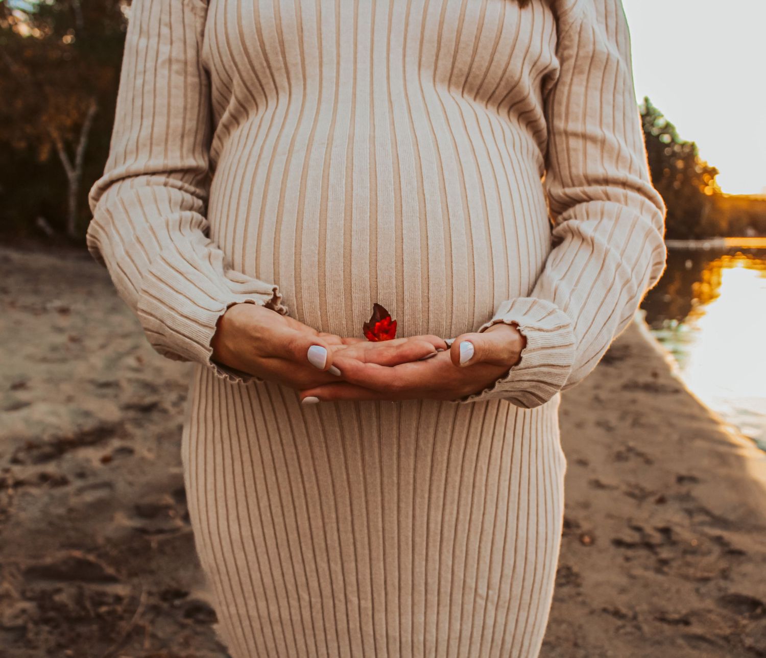 Pregnant belly holding a leaf on a beach in Maine