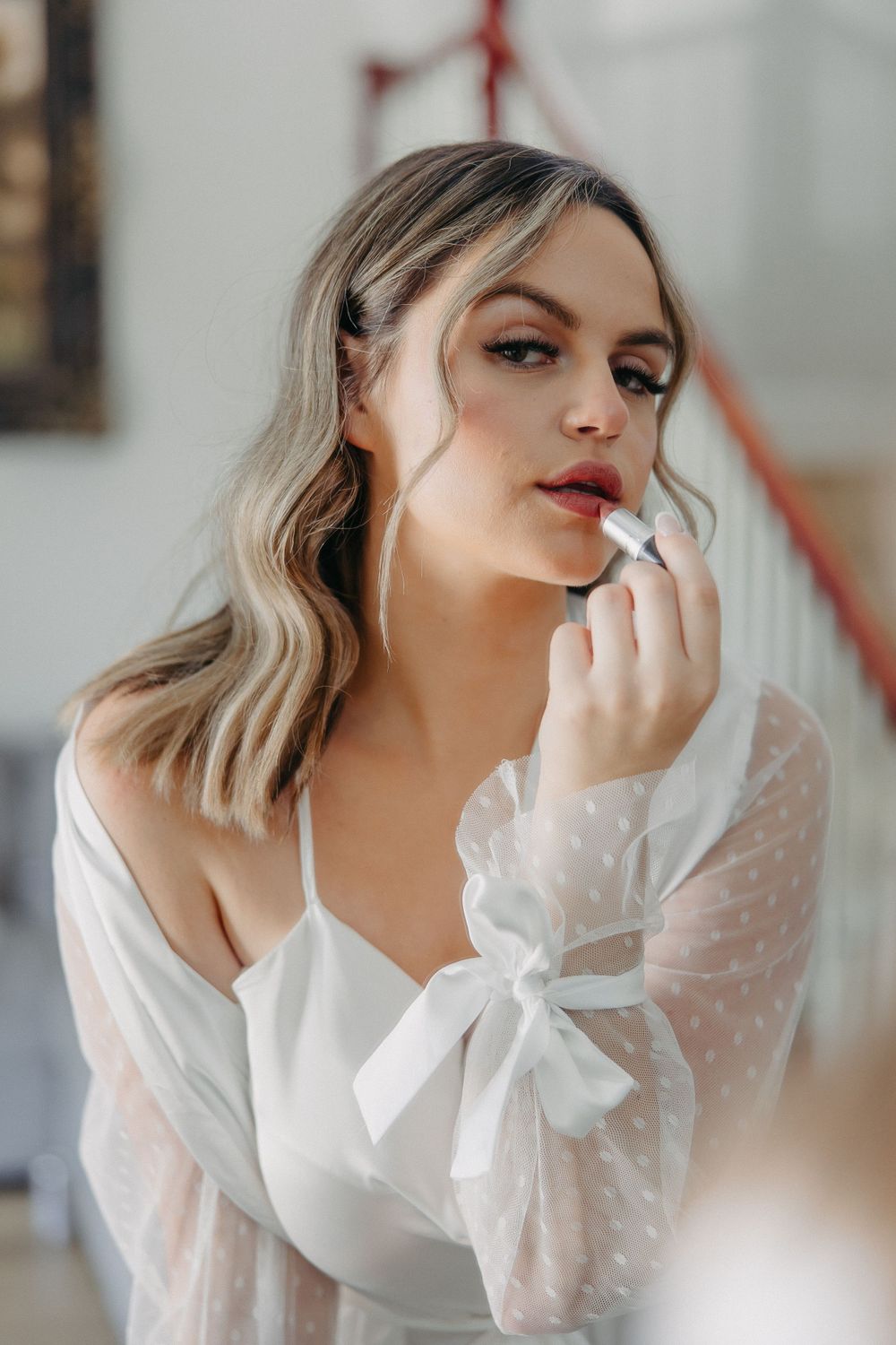 A bride in white getting final makeup touches during wedding preparations.
