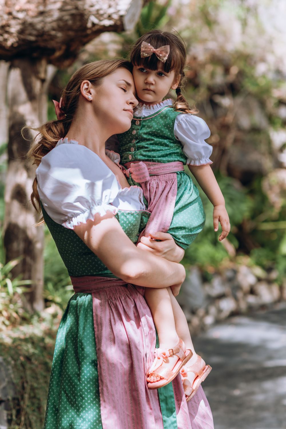 Two people in traditional dirndl dresses standing by a stream in a natural setting.