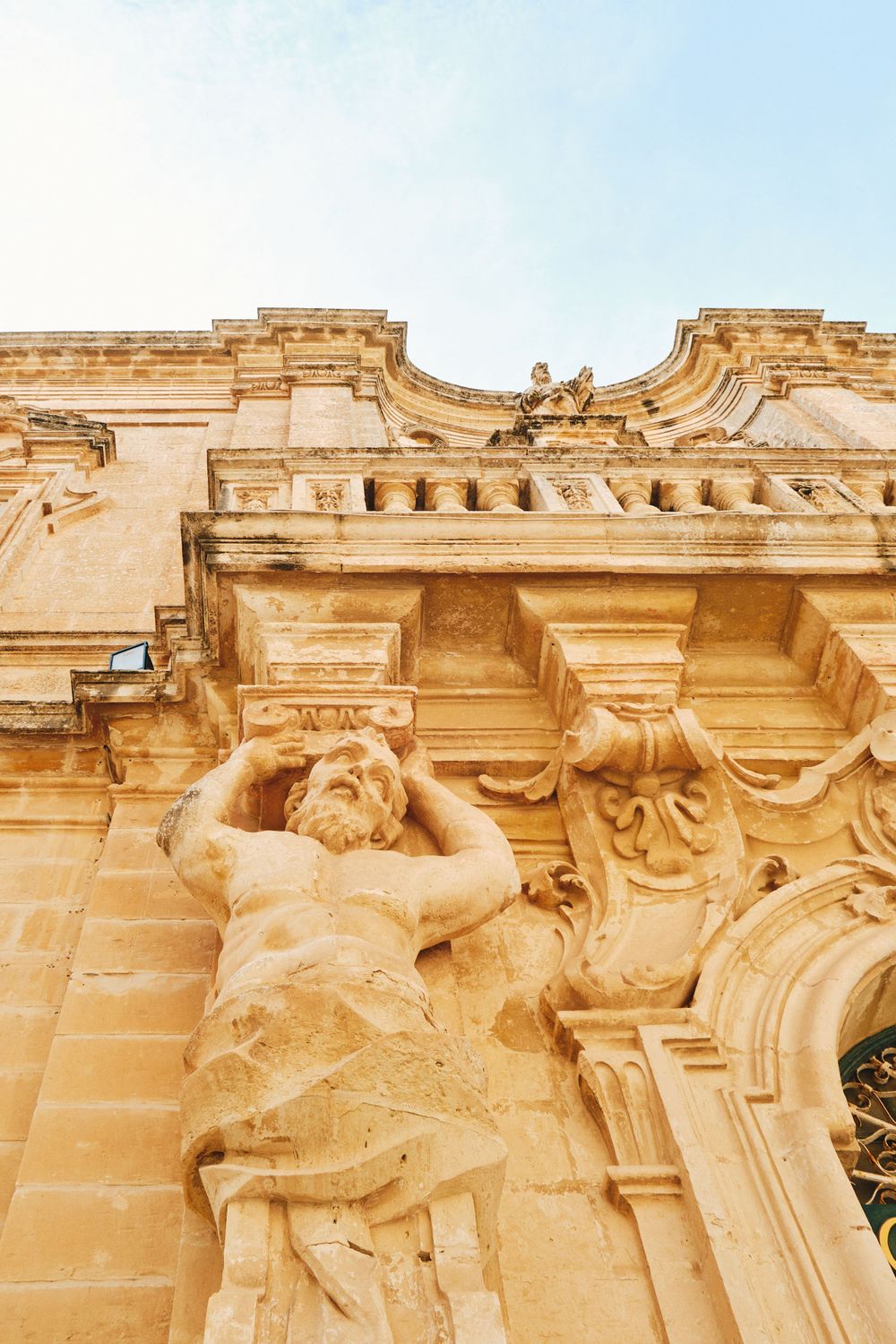 Detailed baroque stone carving of a classical figure on a historic building facade.