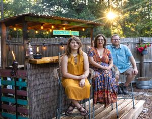 Casual group enjoying evening drinks at rustic backyard tiki bar with string lights.