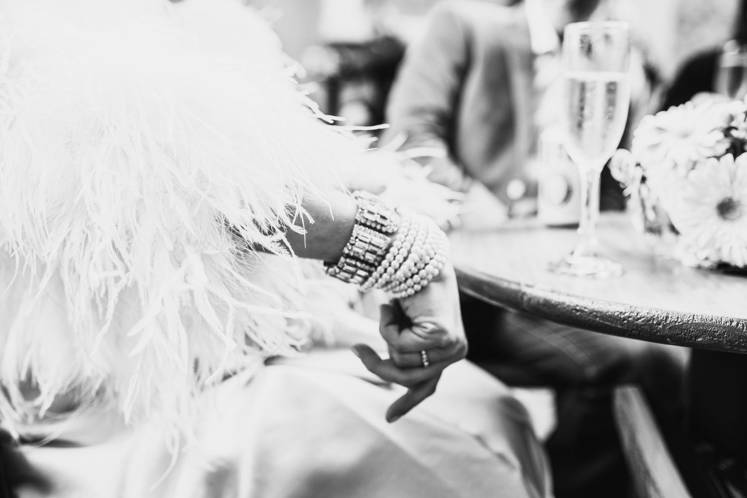 Close-up shot of hands wearing rings against white feathers.