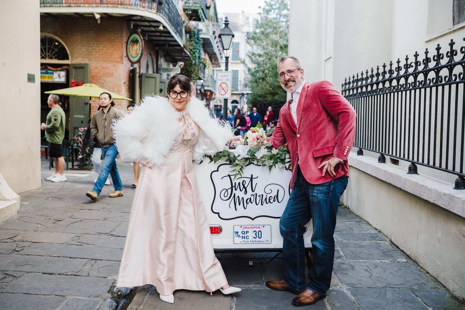 A couple poses next to a 'Just Married' sign on a historic street.