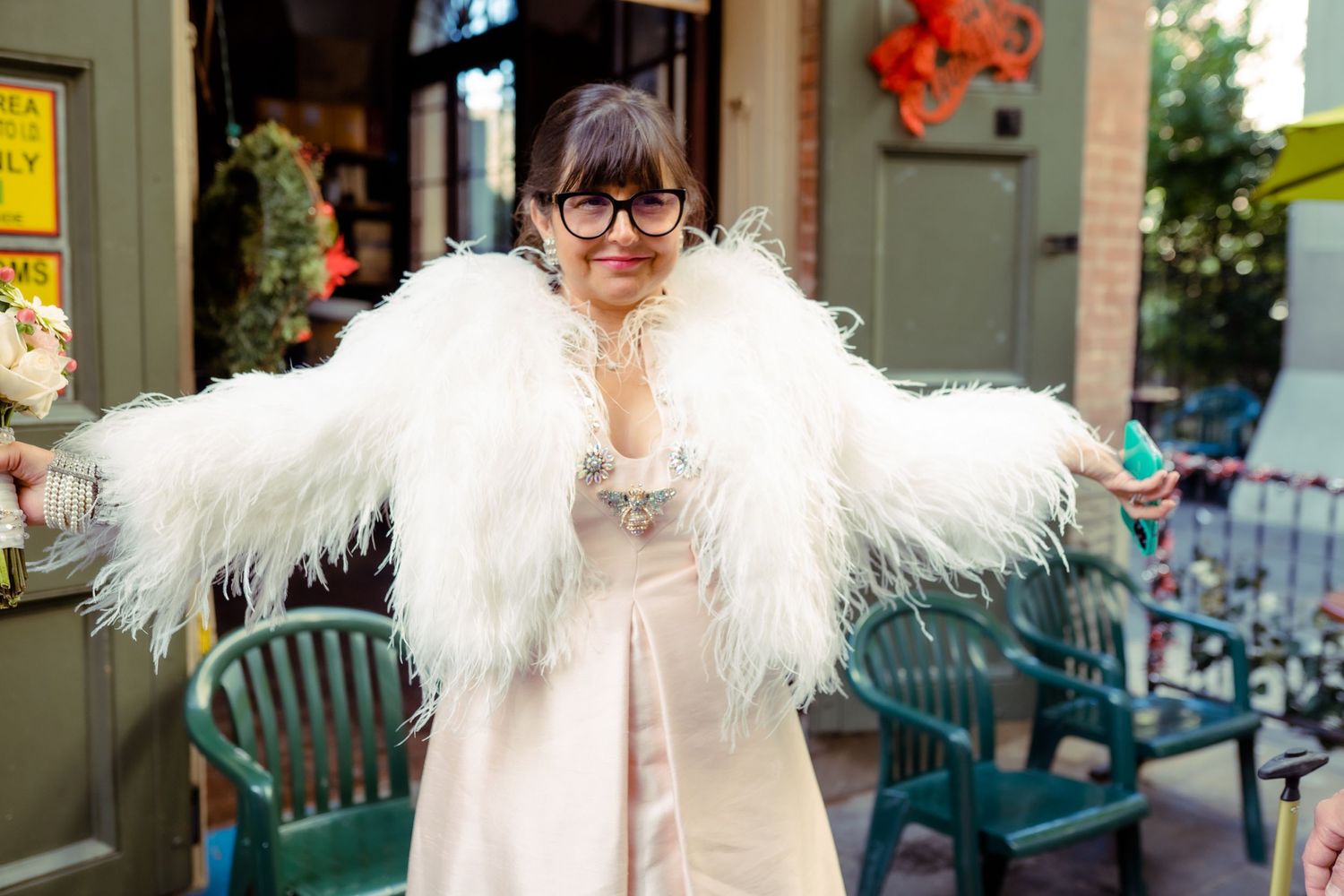 A glamorous outfit featuring a dramatic white feathered shawl and glasses on a city street.
