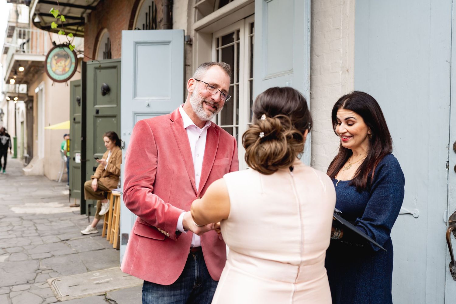 A group conversation in front of a historic building with someone wearing a pink blazer.