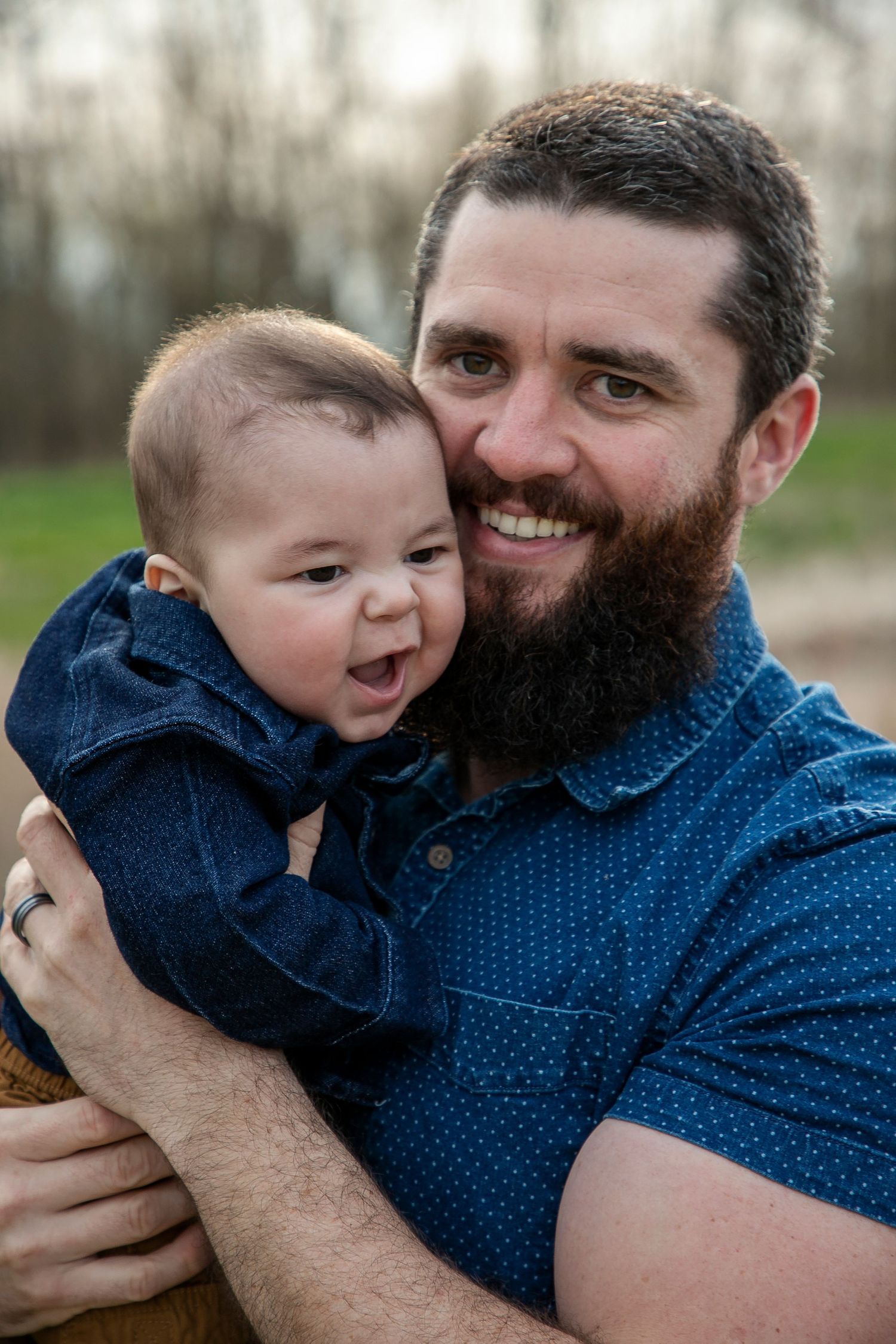 A father holding his baby boy up to his face smiling at the camera