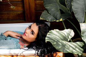 Artistic portrait beside large tropical leaves featuring elegant makeup and styling.