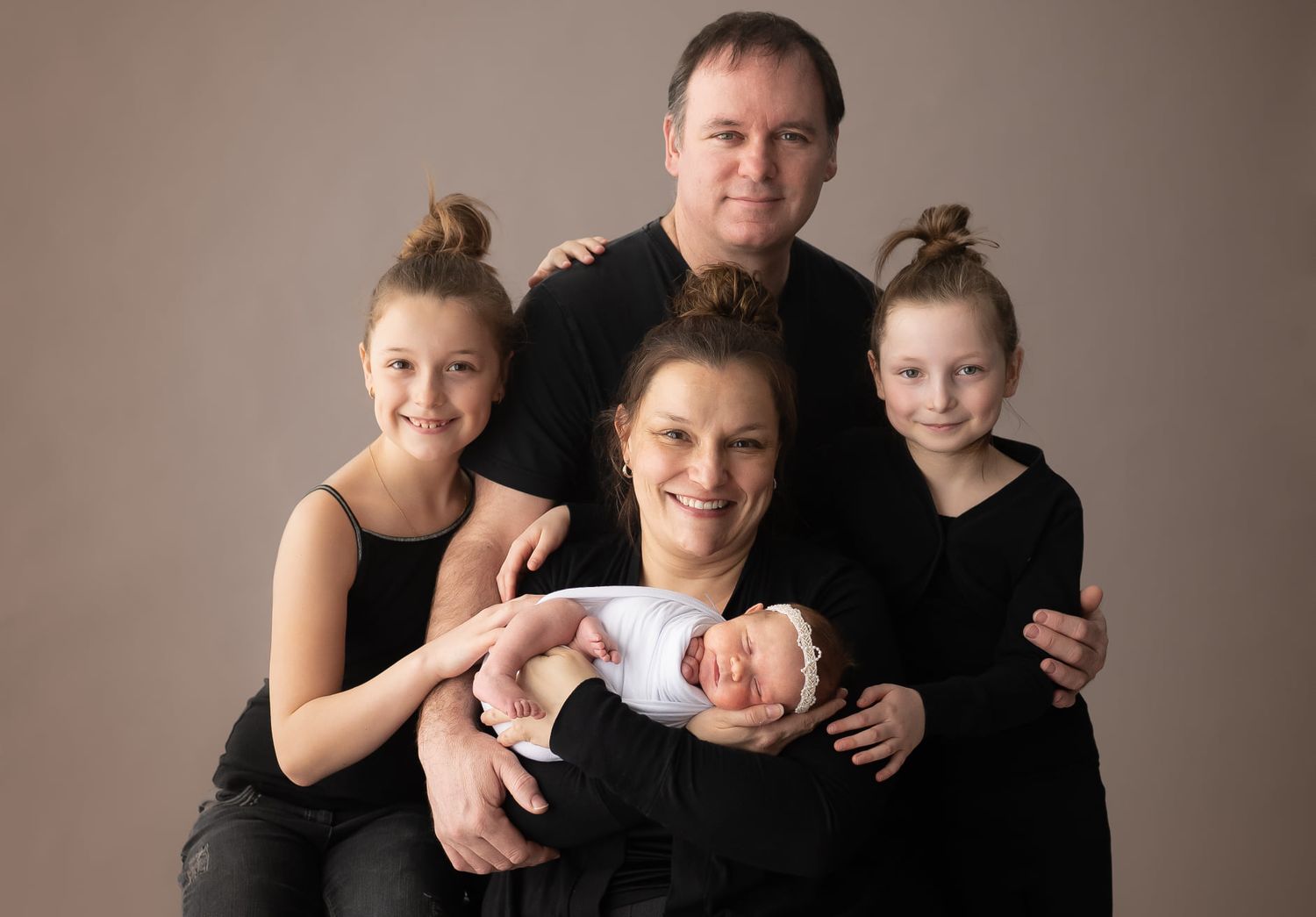 Family studio portrait in black outfits with newborn baby.