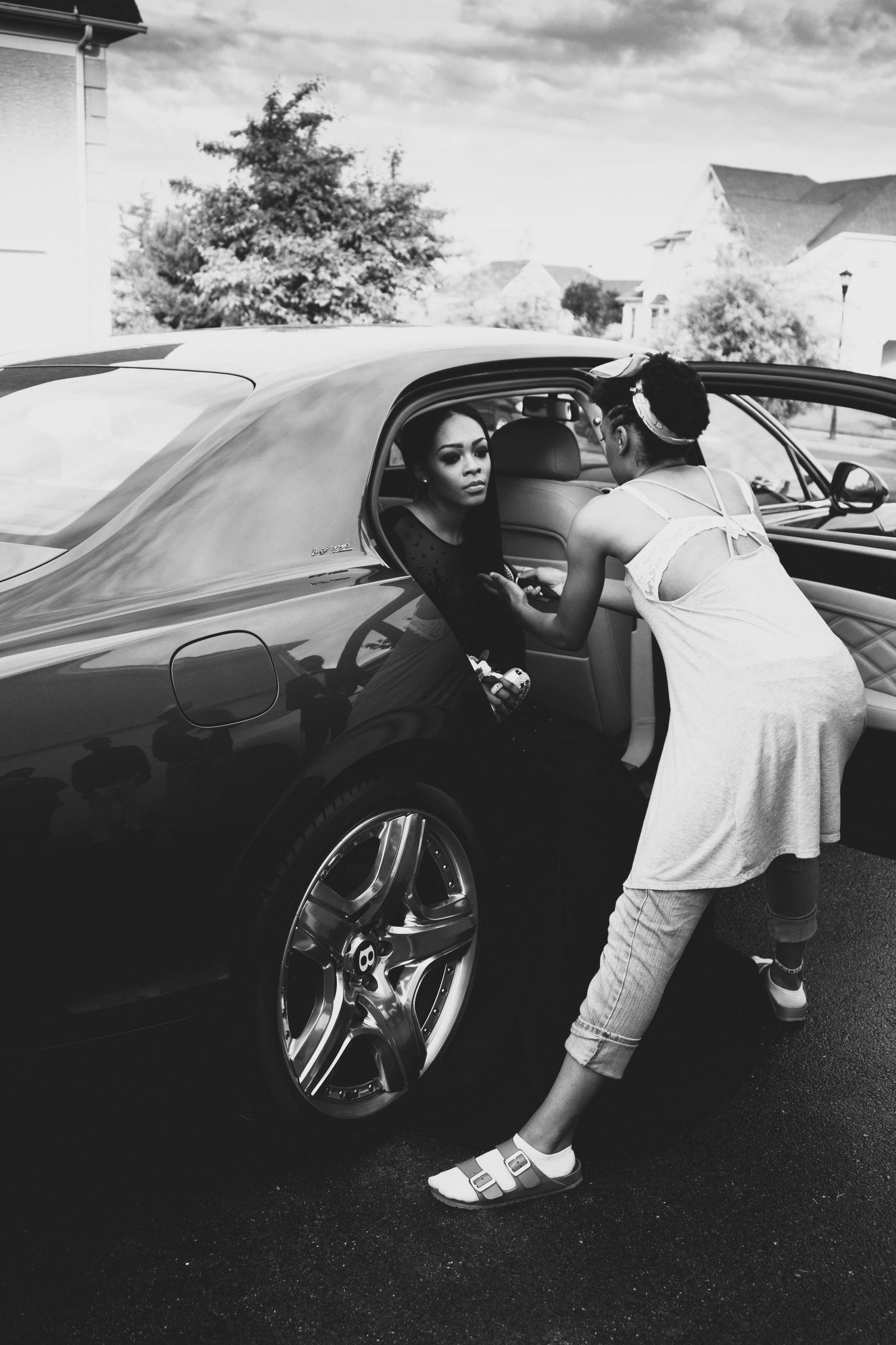 Black and white photos showing someone getting into a luxury car wearing a formal gown.  L Visions Photography. Prom photoshoot.