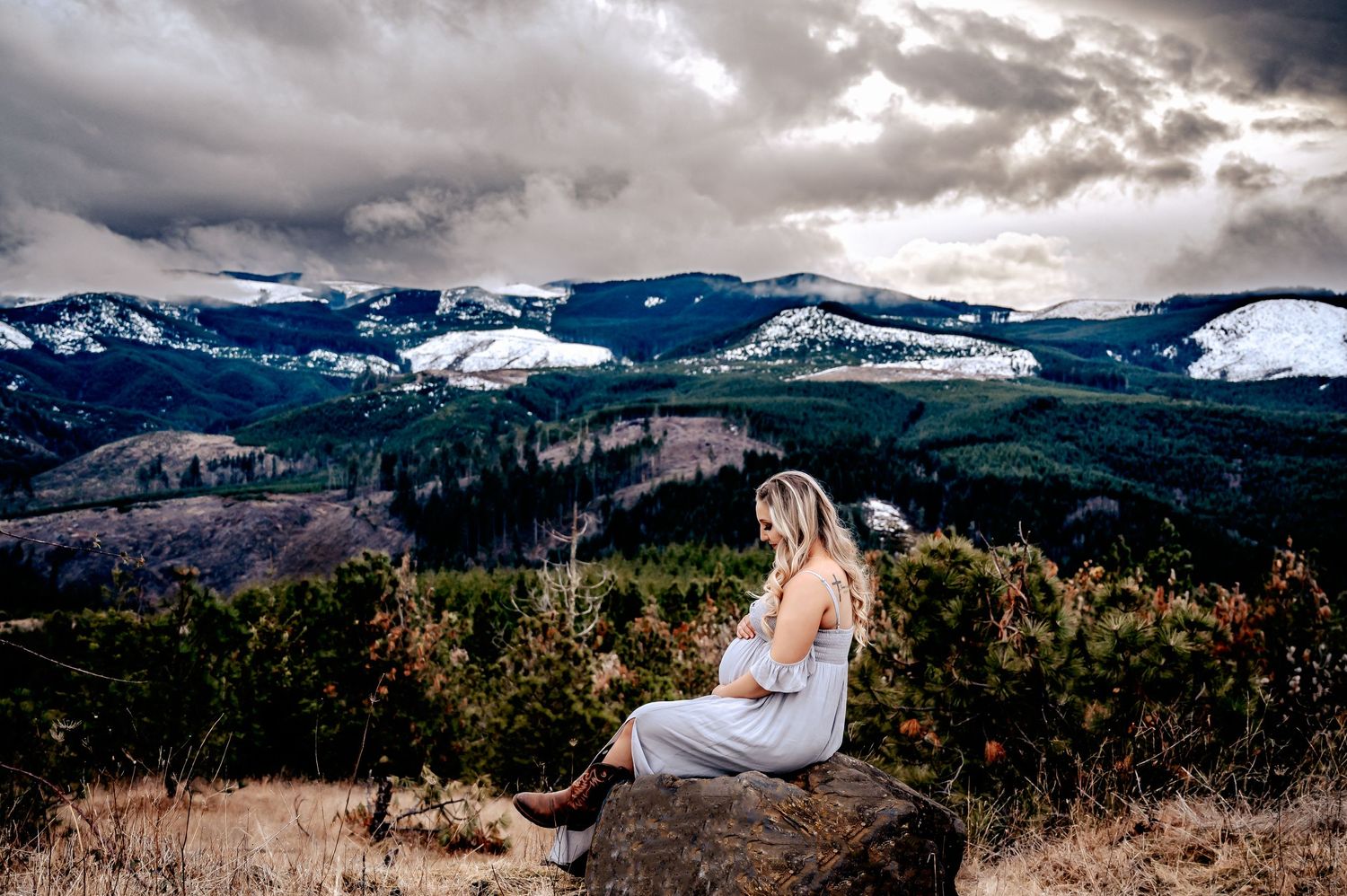 Dramatic mountain landscape with snow-capped peaks under moody clouds in a panoramic view.