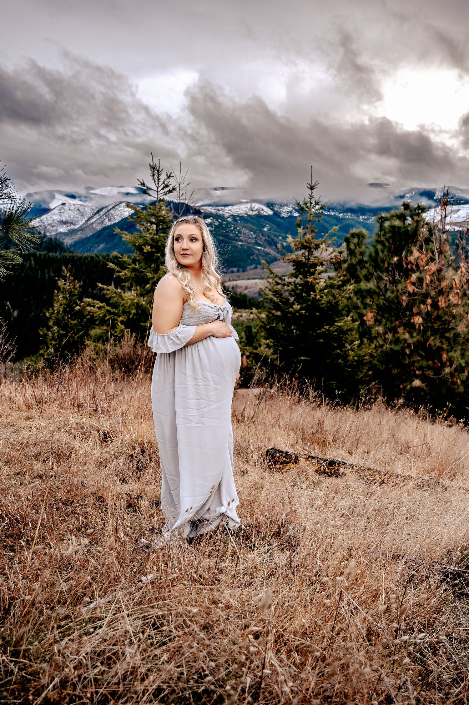 Ethereal mountain landscape with figure in flowing dress against dramatic cloudy sky.