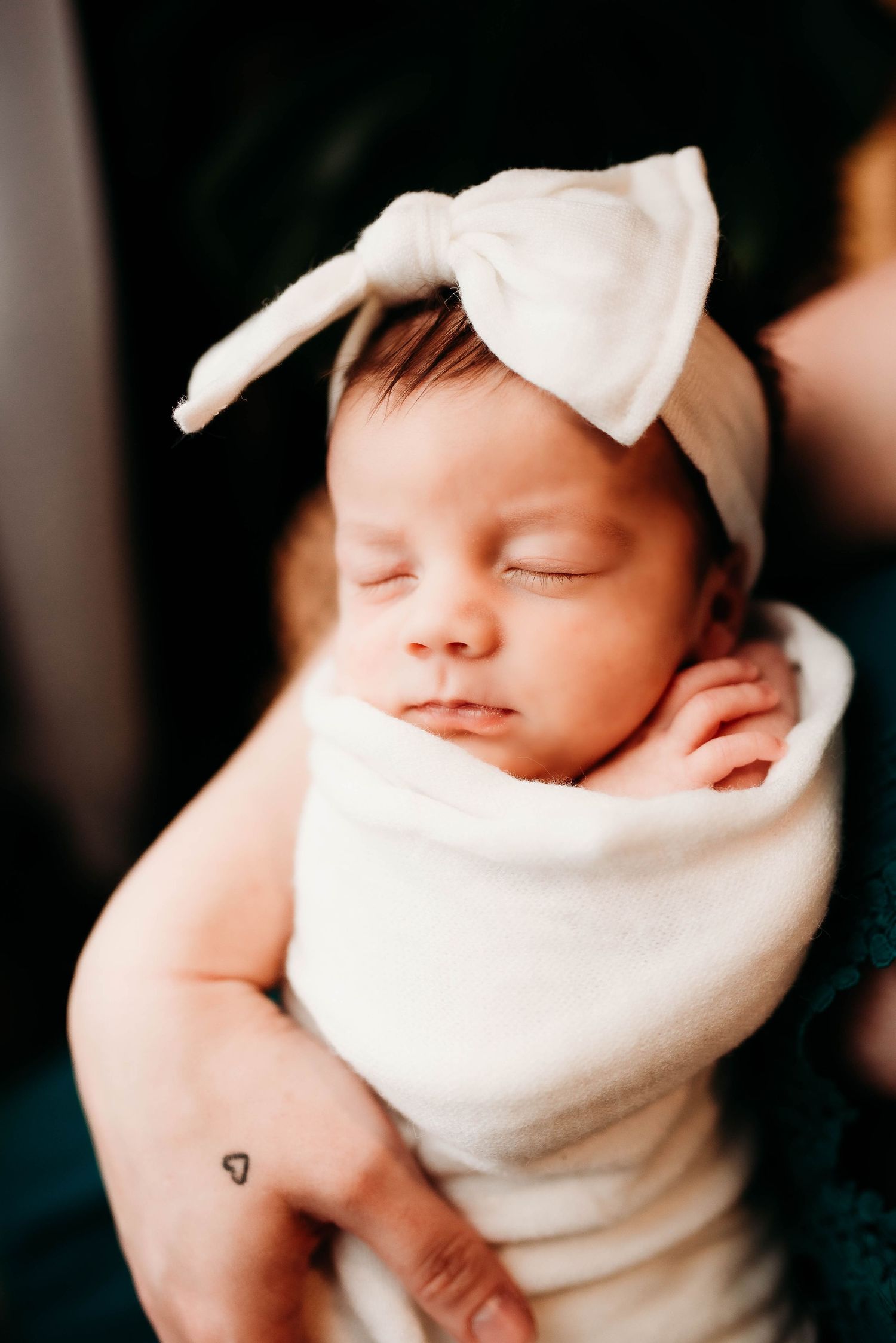 Close-up portraits of a peaceful sleeping newborn swaddled in white.
