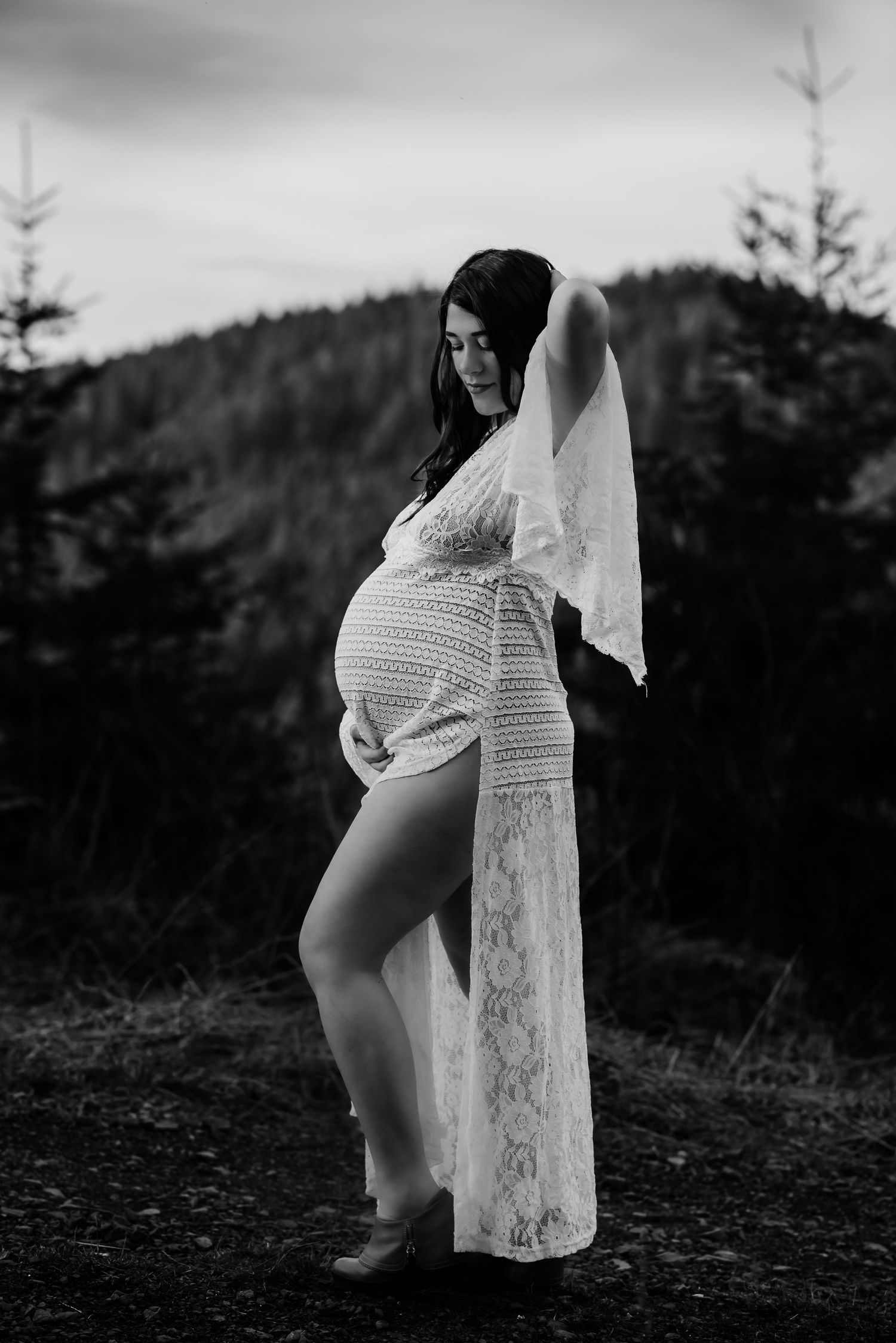 Black and white maternity photos showing a lace dress against a mountain backdrop.