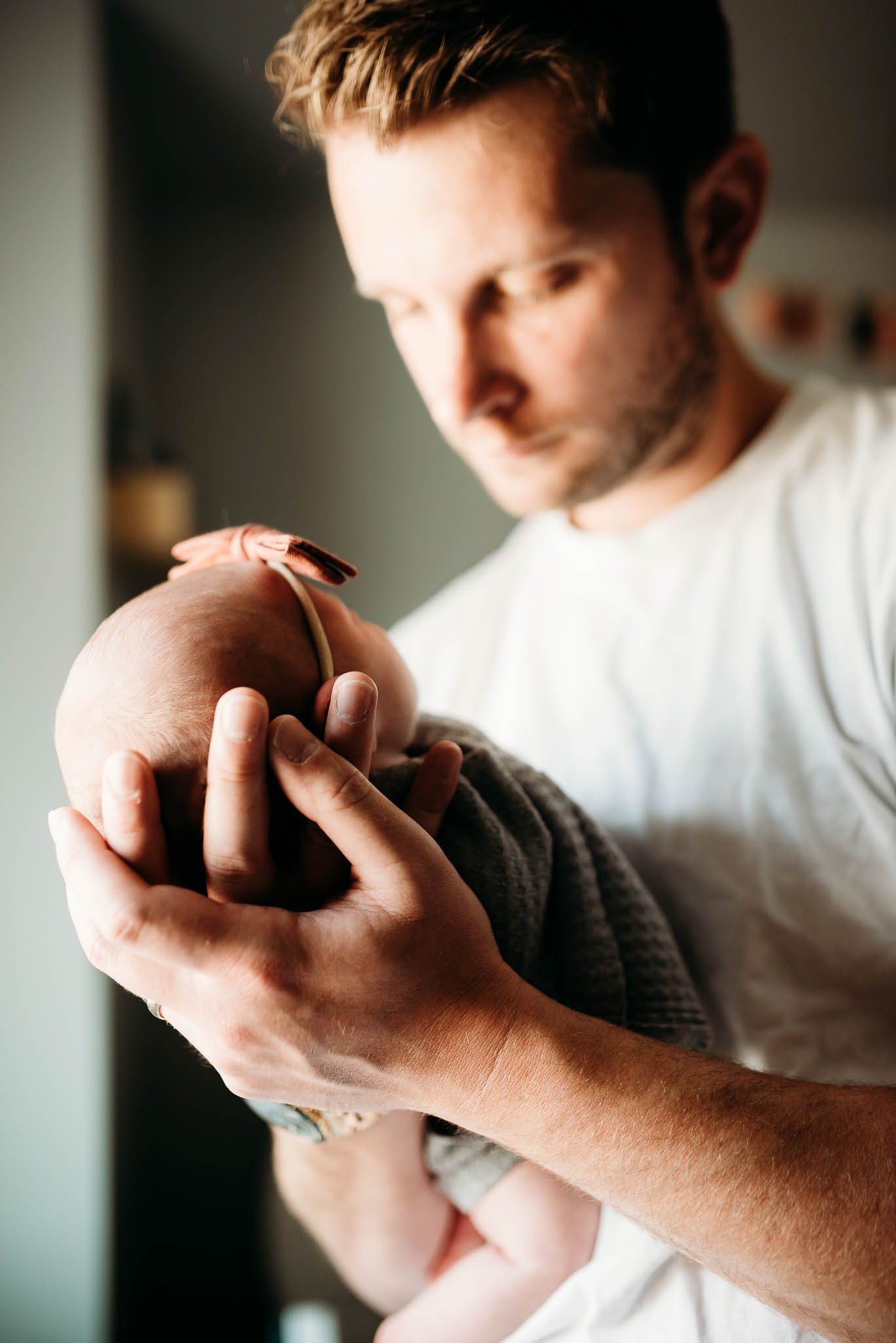 Close-up series of hands gently holding and caressing a newborn baby in soft lighting.
