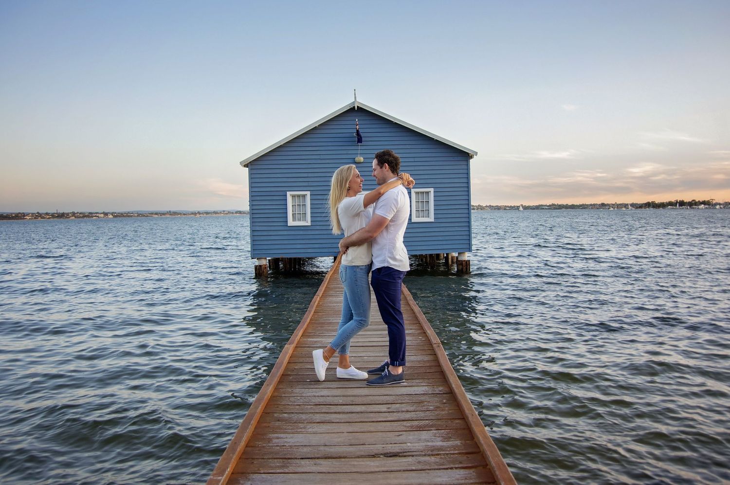 couple embracing infront of blue boat house perth