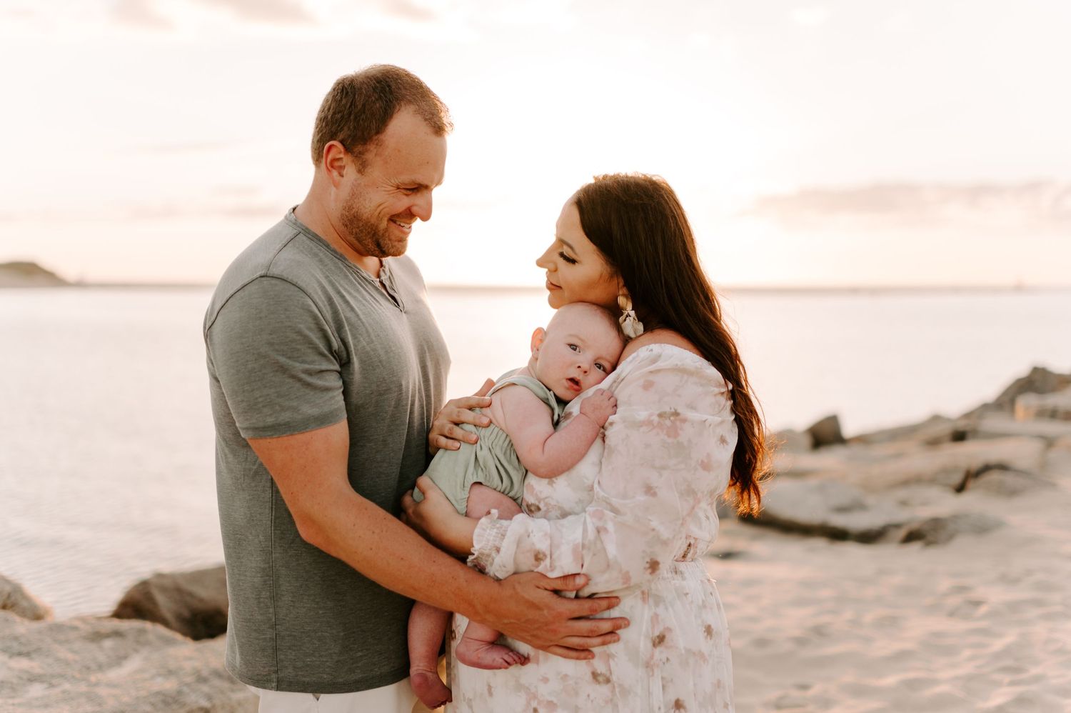Family sharing intimate moments on the beach at sunset.