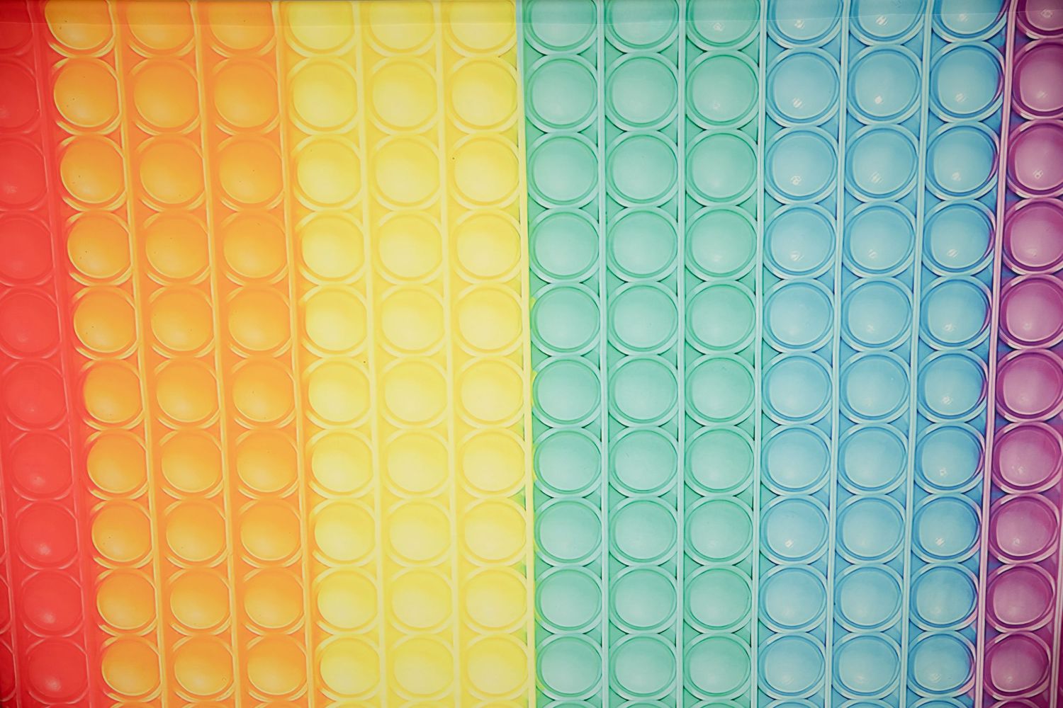 Close-up of rainbow colored bubble pop fidget toy showing circular dimpled pattern.