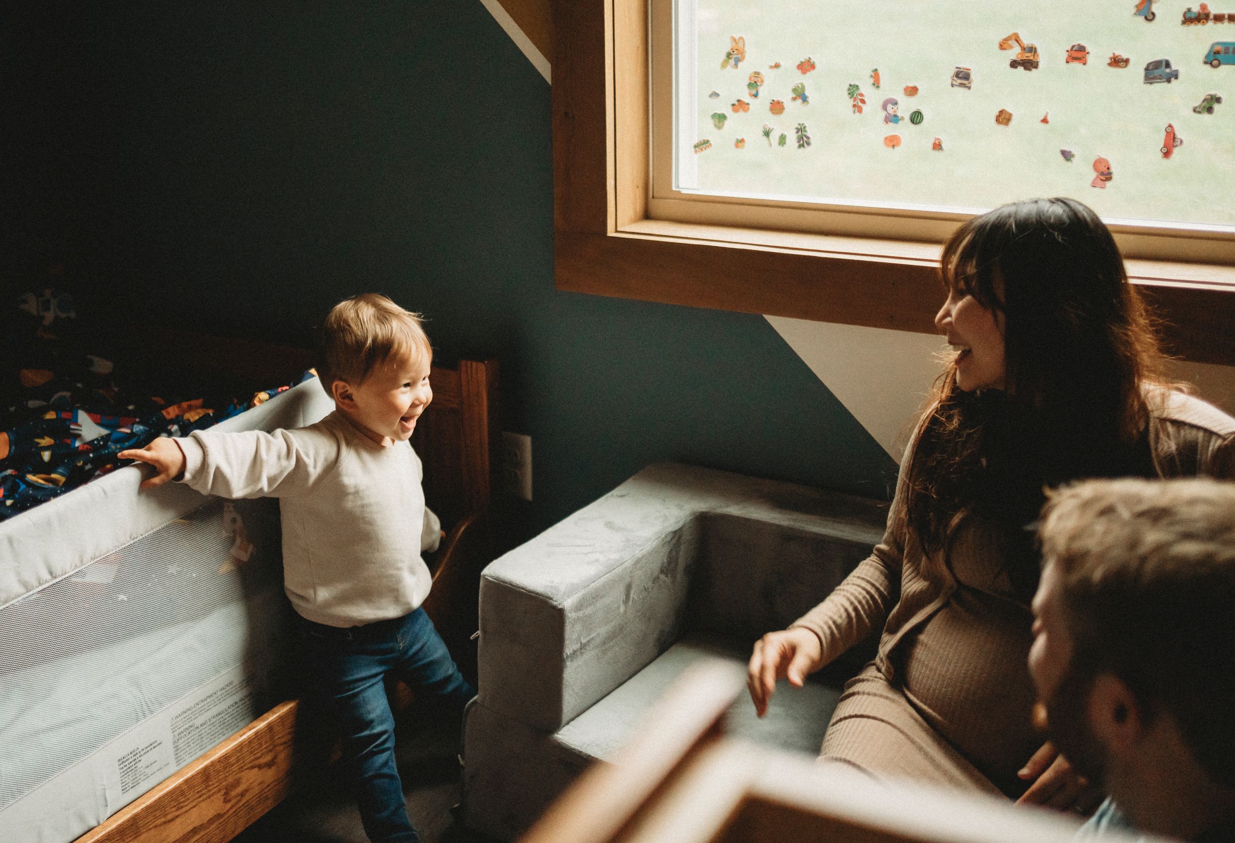 A small child in white sweater plays energetically near a window in a cozy room.