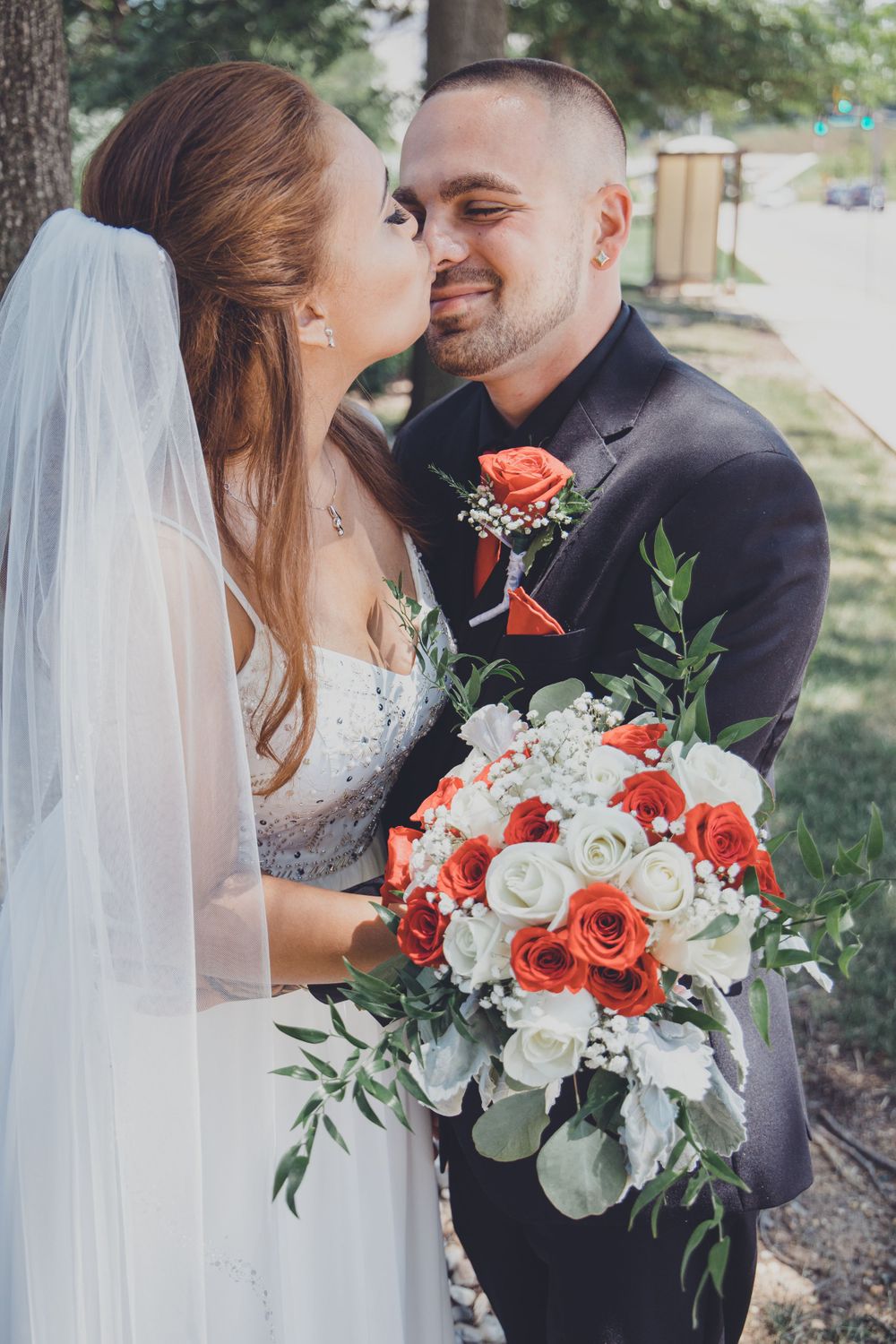 A tender wedding moment captured with a beautiful coral and white rose bouquet.
