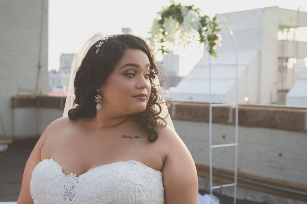 Bride in white dress poses elegantly against industrial backdrop.