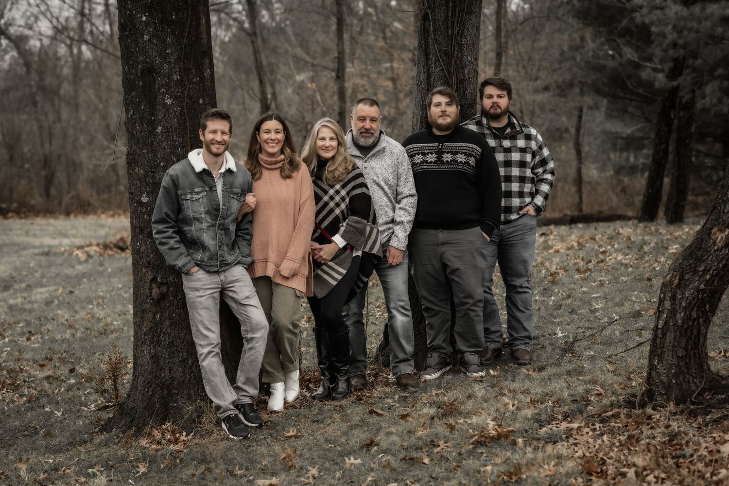 A casual group photo of friends standing together against bare trees on an overcast day.