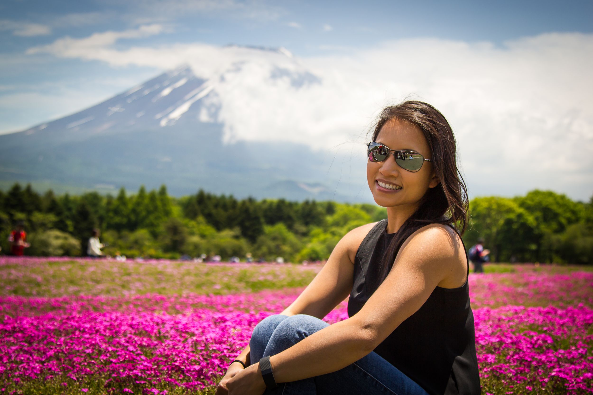 Portrait of asian girl sitting in front of pink flowers with Mf. Fuji in the background.