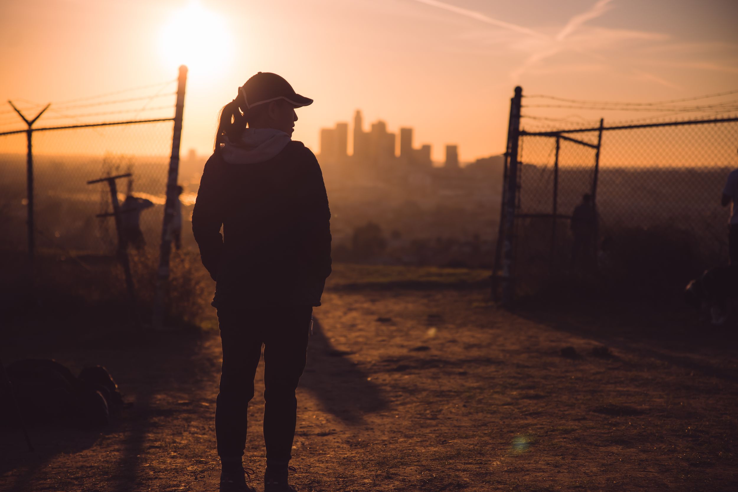 Sunset silhouette of girl with downtown Los Angeles in the background.