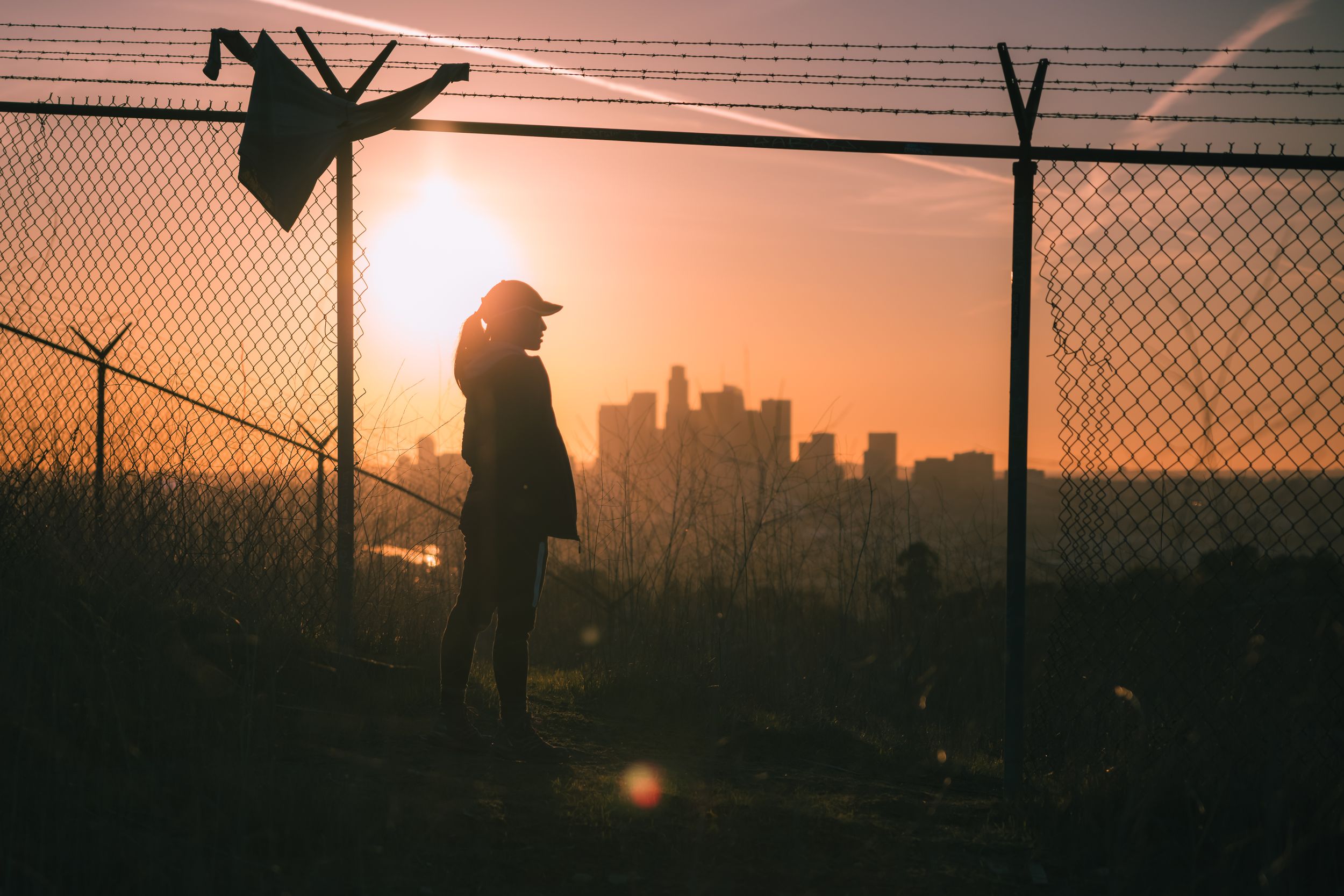 Sunset silhouette of girl and downtown Los Angeles.