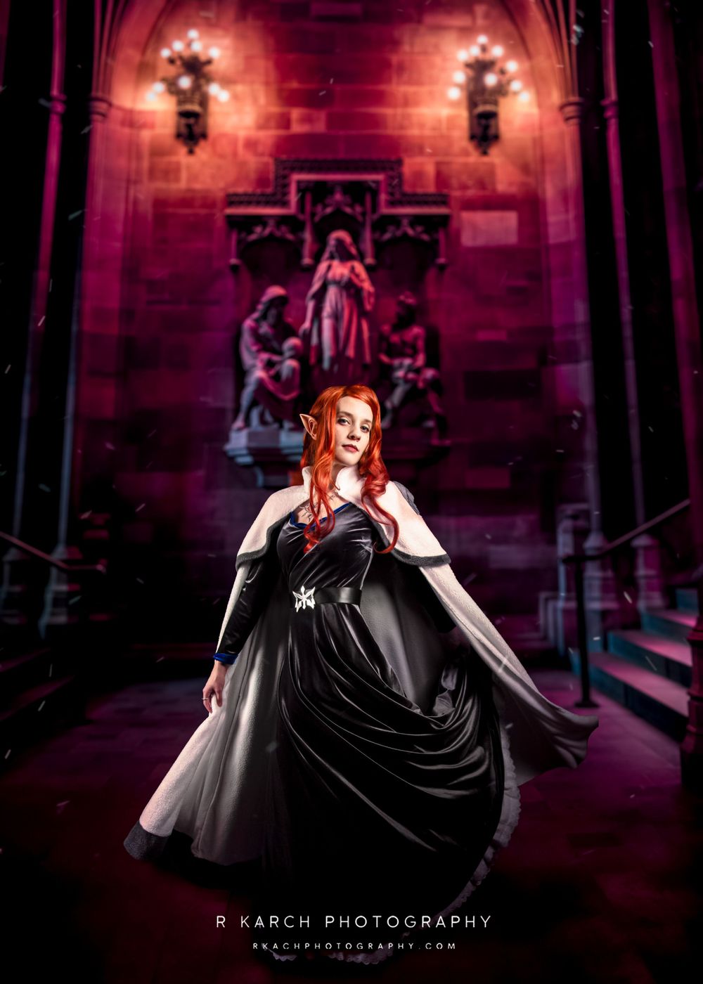 Dramatic gothic fashion photography in red-lit cathedral interior with figure in flowing black dress.