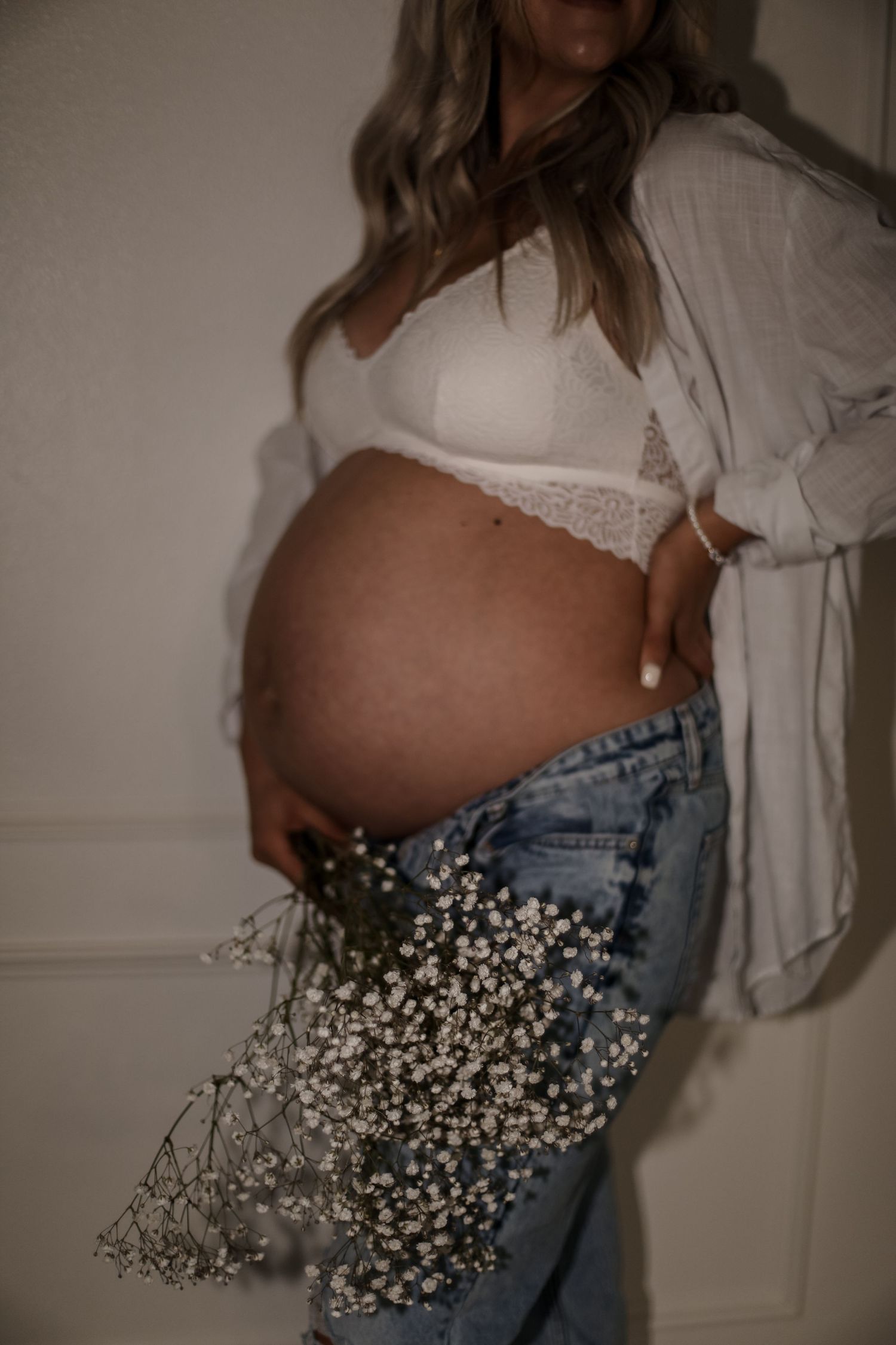 Romantic maternity portrait with baby's breath flowers and white lace details.