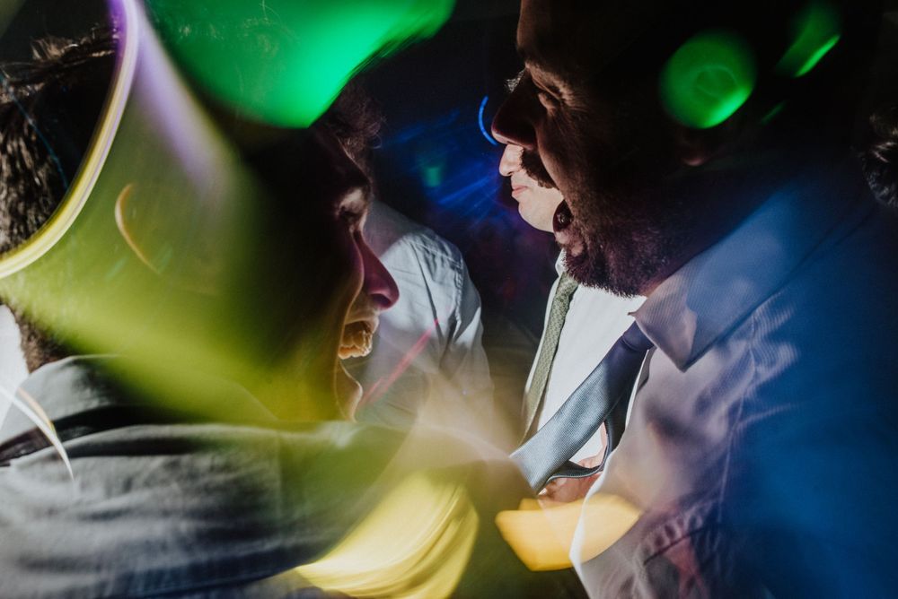Couple sharing an intimate moment surrounded by colorful green and blue party lights.