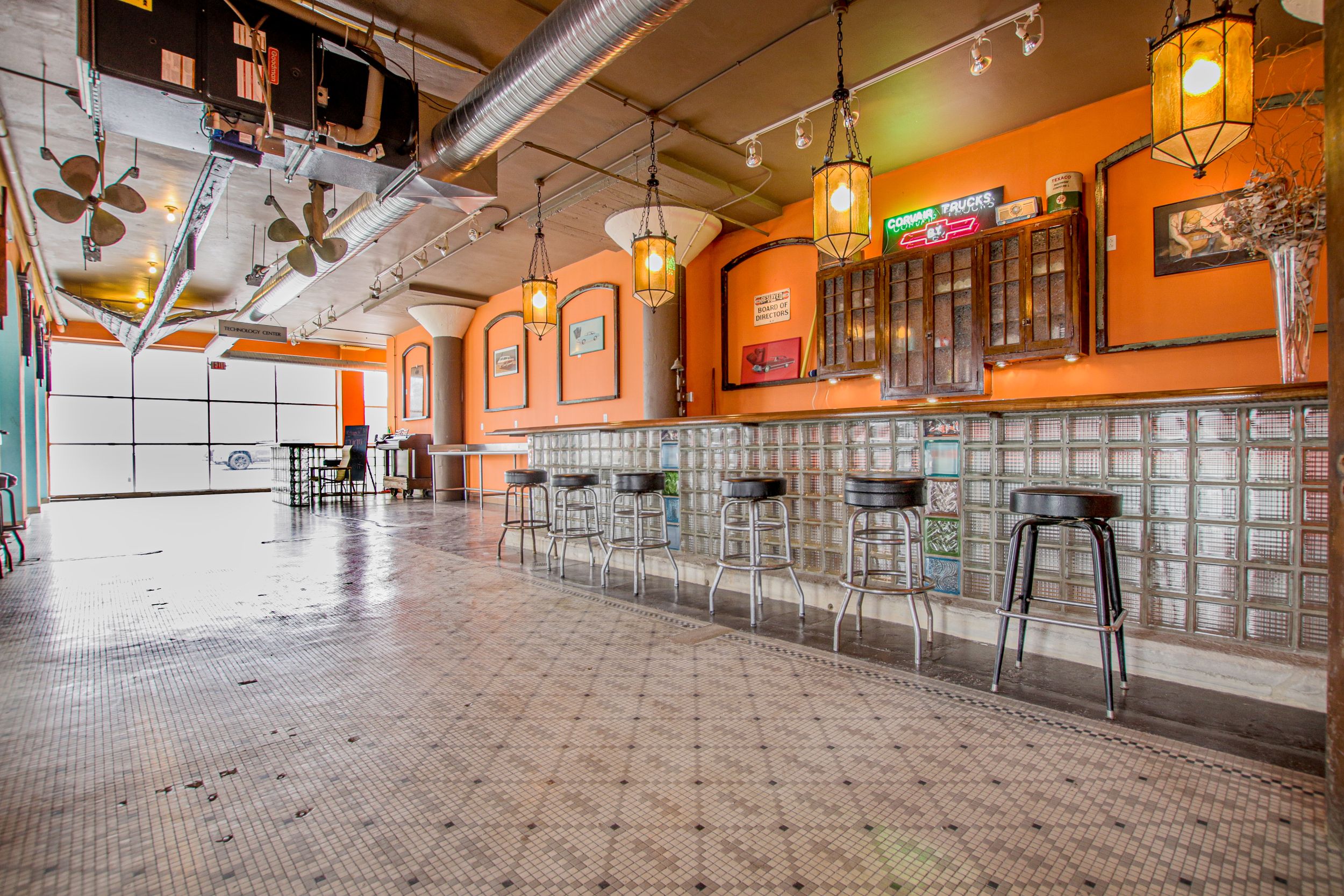 Restaurant interior with orange walls, pendant lighting, and bar seating.
