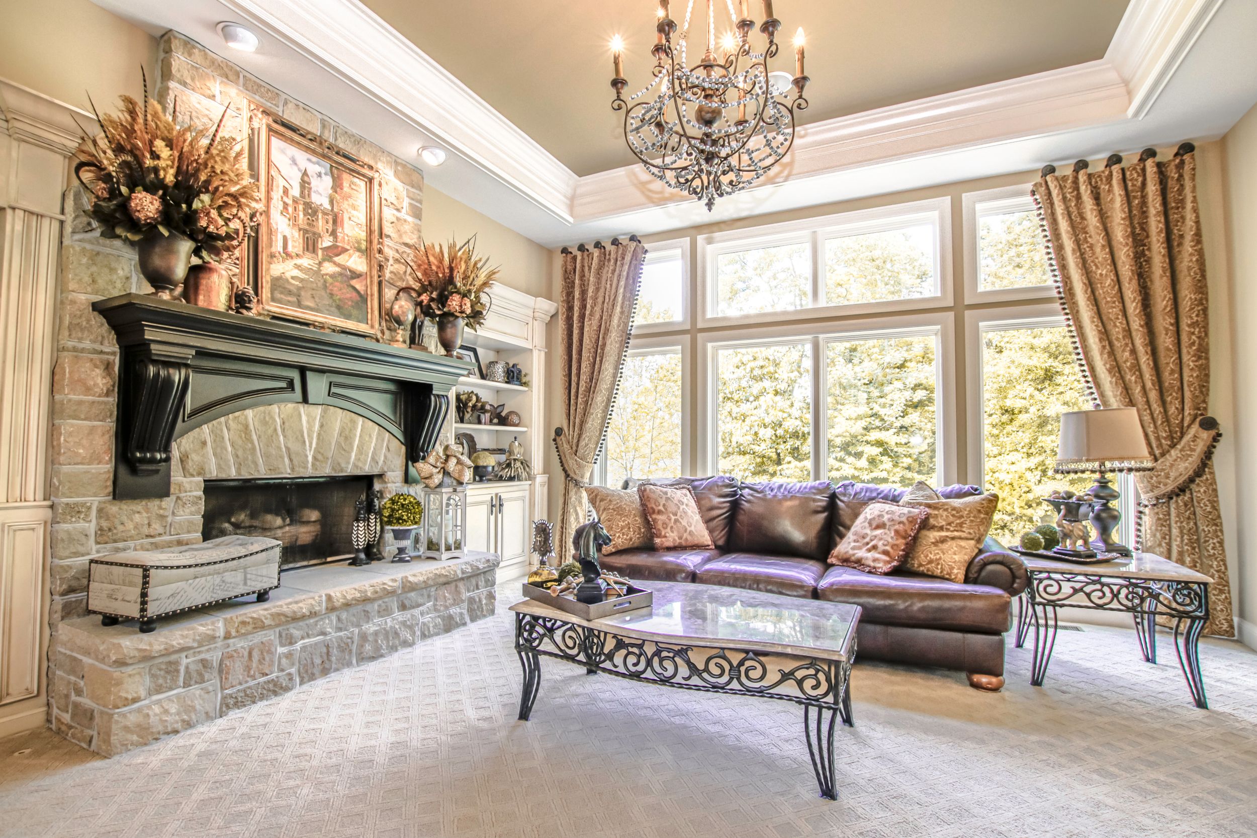 Luxurious living room with stone fireplace, crystal chandelier, and elegant furnishings.