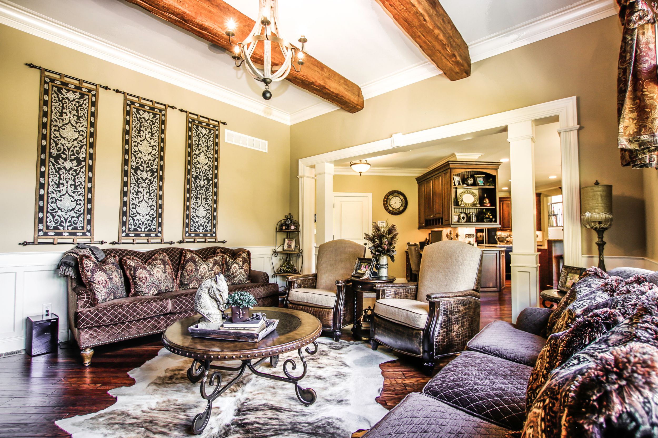 Elegant living room with exposed wooden beams, ornate furniture, and decorative wall panels.