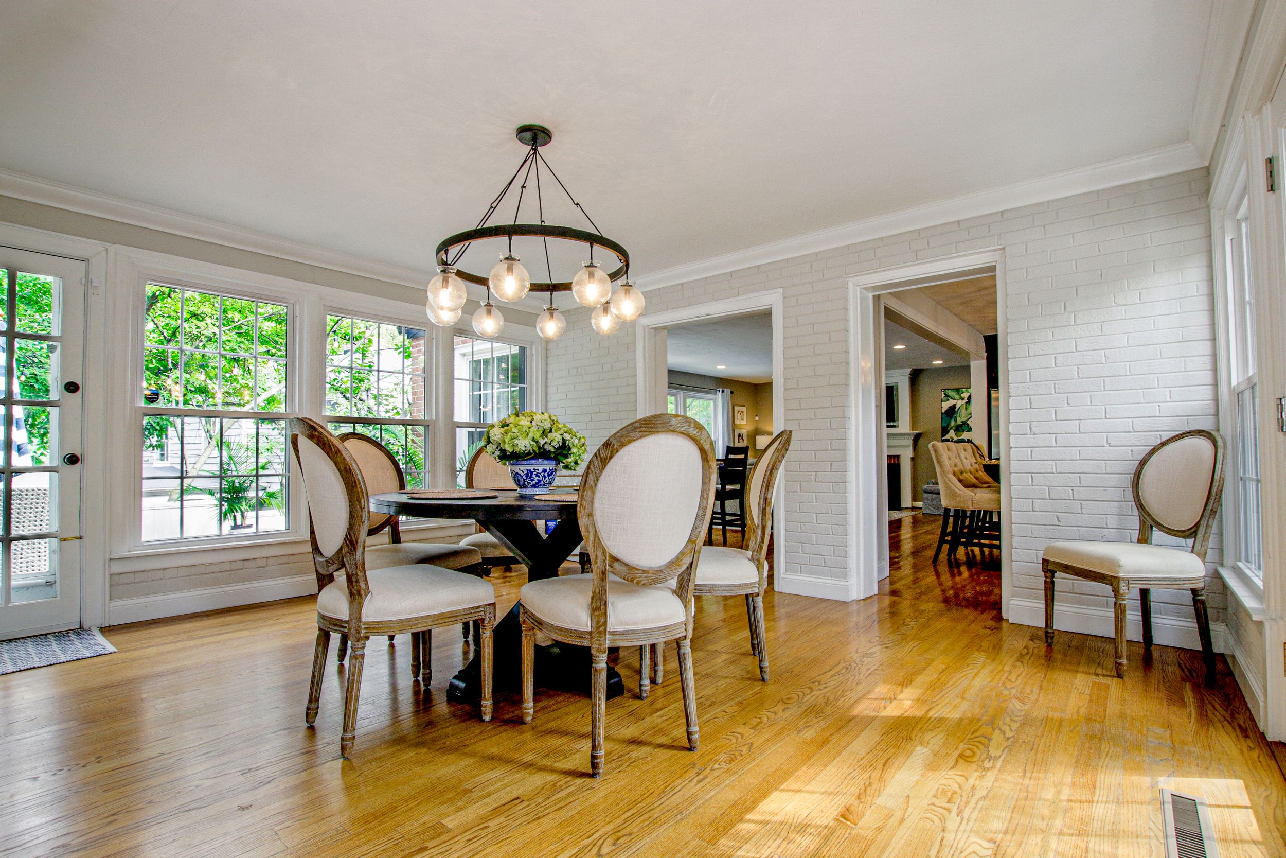 Elegant dining room featuring French chairs, chandelier, and large windows with natural light.