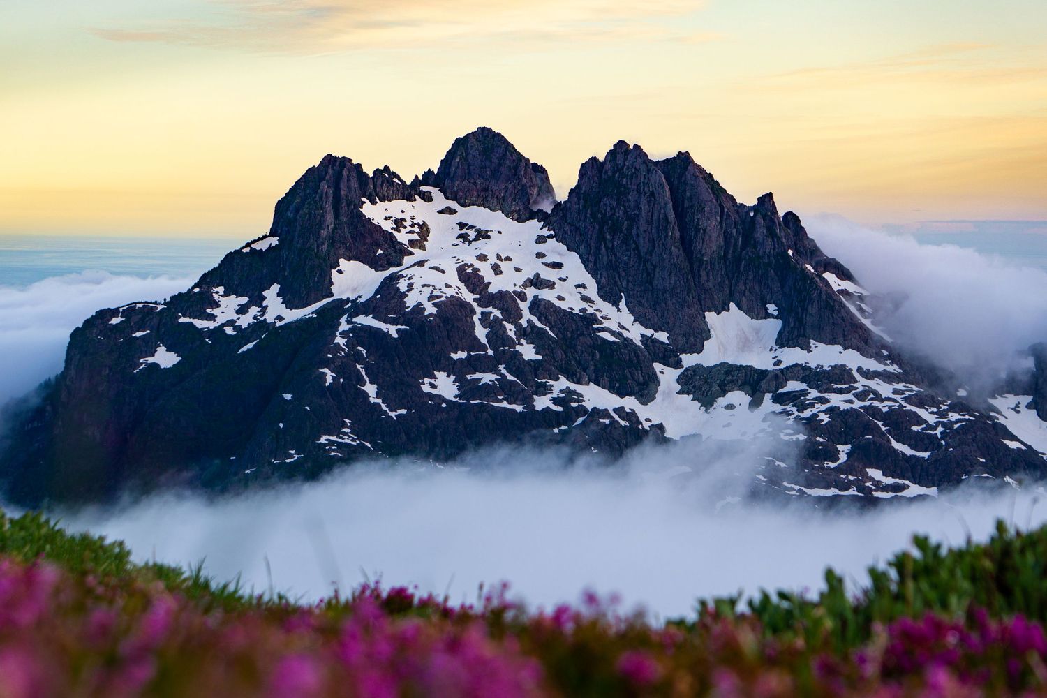 Mountain surrounded by clouds at sunset. Photo taken by colin pendziwol
