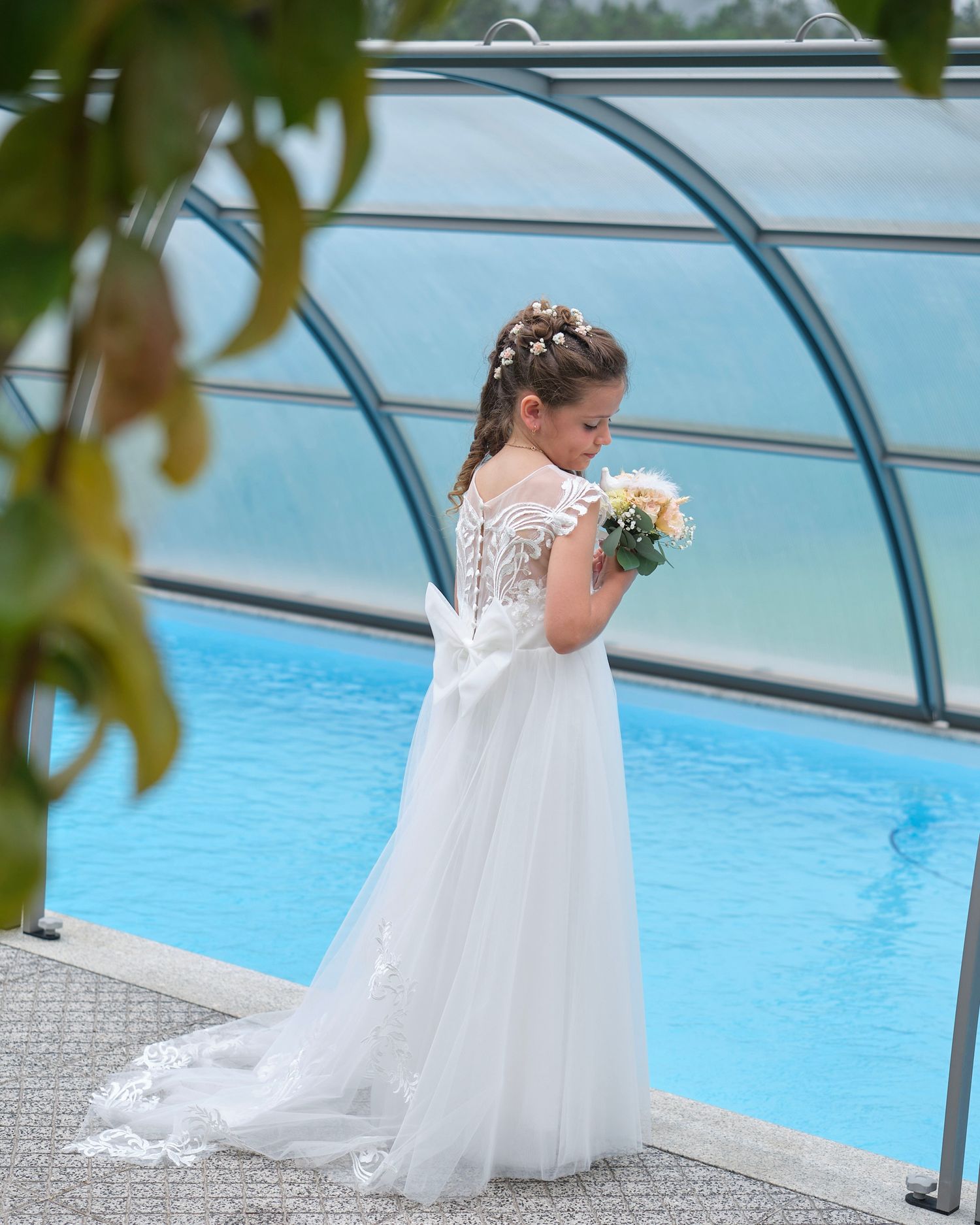 Menina com vestido de comunhão pelo da piscina