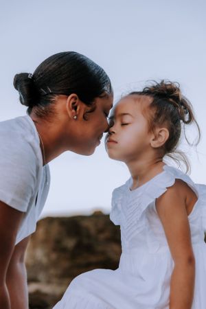 Two people share an intimate moment against a bright sky background.