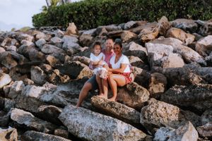 Family relaxing together on rocky coastal terrain by the ocean.