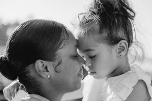 Two people share an intimate close-up moment against a bright background.