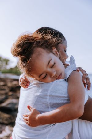 A small child in white clothing is held in a warm embrace.